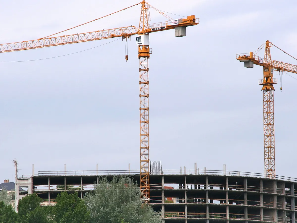 Turmkräne über dem Betonrohbau eines Gebäudes im Bau