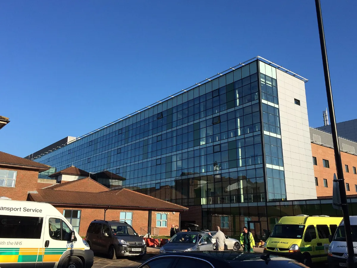 Gläsernes Hauptgebäude eines Krankenhauses mit Rettungswagen davor